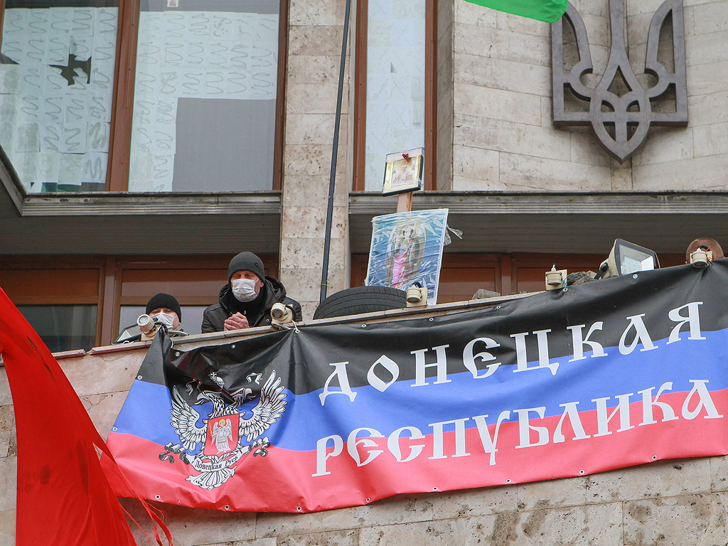 Про-руски протестиращи развяват плакат с надпис Донецка Република на балкона на окупираната сградата на областната администрация, в Донецк, Украйна