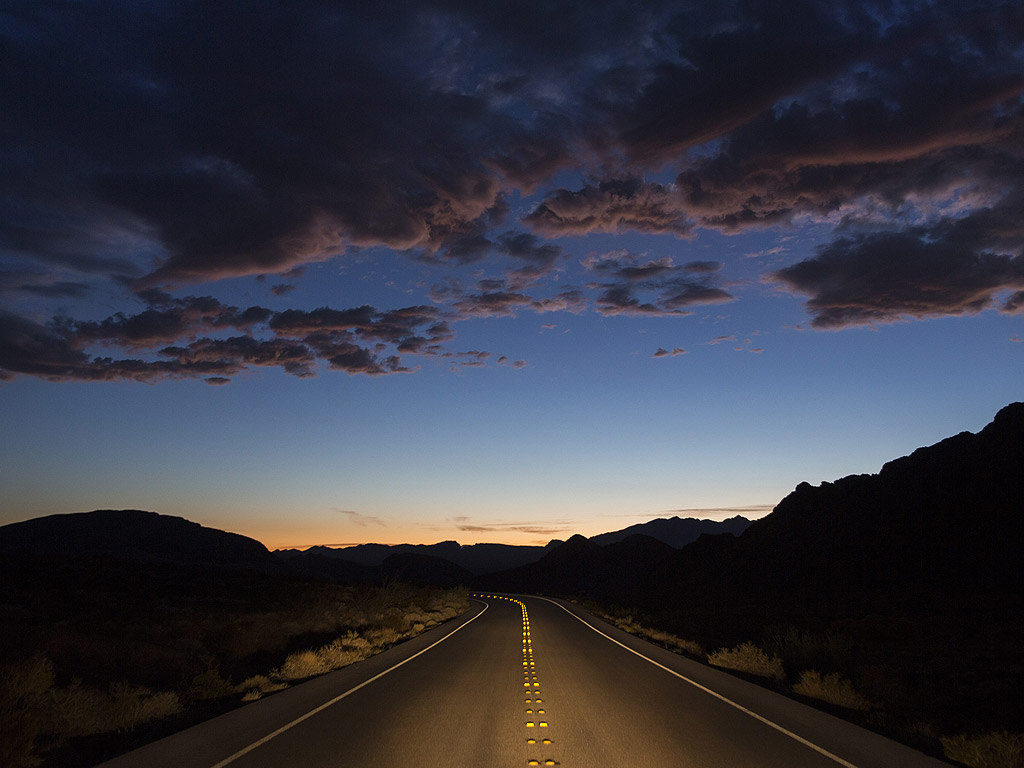Автомобилни фарове осветяват магистрала 168 привечер в Националната зона за отдих на Невада, САЩ