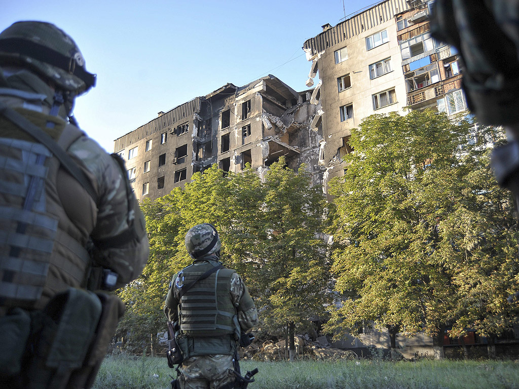 Украински войници разглеждат разрушена сграда в Лисичанск, район близо до Луганск