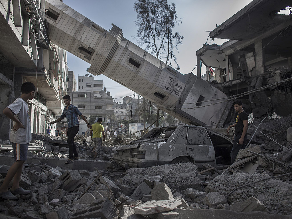 Палестинци до рухналото минаре на разрушена джамия в град Газа, Ивицата Газа. Джамията е разрушена през ноща след израелски въздушен удар