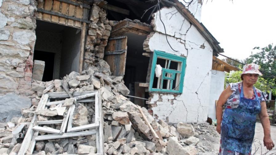 Жена оглежда разрушенията на къщата си в Петровка, на около 20 км от Донецк