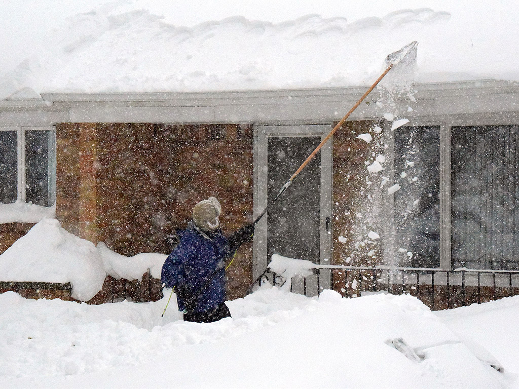 Човек използва дълга рибарска мрежа, за да отстрани снега от покрива на къщата си. Снегът достигна 1,5 метра в района, в Хамбург, Ню Йорк, САЩ. Няколко покрива са се сринали под тежестта на снега, като прогнозите предвиждат още сняг в областта днес, което може да доведе до височина на снежната покривка от 6 фута (1.83 метра)