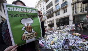 Млада жена държи новия брой на сатиричното издание Шарли ебдо, на чиято първа страница е изобразен просълзения пророк Мохамед, придружен от думите "Всичко е простено"