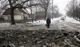 Мъж гледа кратера, образуван от снаряд на централната улица в село Дебатцево, в района на Донецк