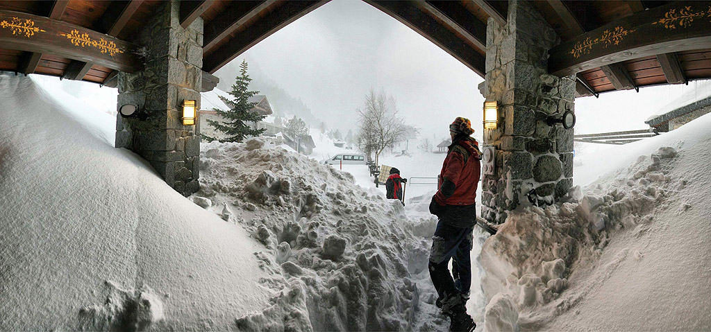 Двама души се опитват да изчистят снега от верандата на къща в ски зоната в Бенаске, Северна Испания.