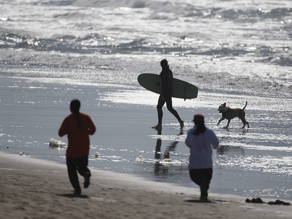 Сърфисти се наслаждават на топлото време в Оъшън Бийч в Сан Франциско, Калифорния, САЩ. в Калифорния и района на залива на Сан Франциско се радват на най-топлата зима от както се водят записи за температурите