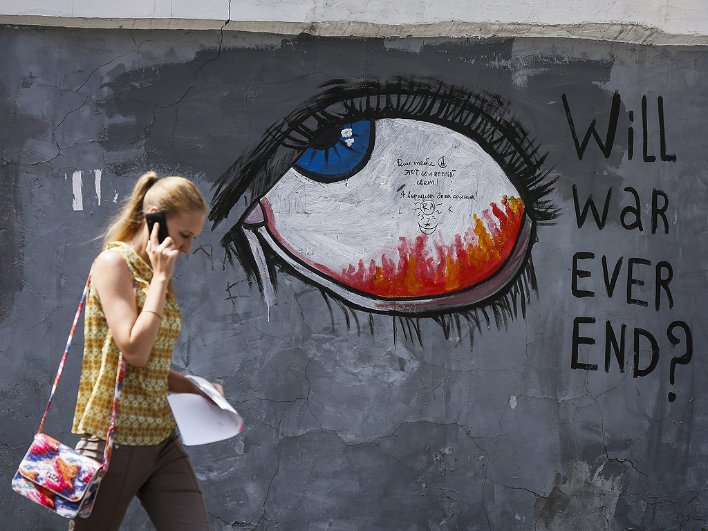 Жена преминава до графит на който се чете "Някога ще свърши ли войната" В центъра на Киев, Украйна. Повече от 6000 души са били убити в източната част на Украйна, от април миналата година, според оценка на ООН.