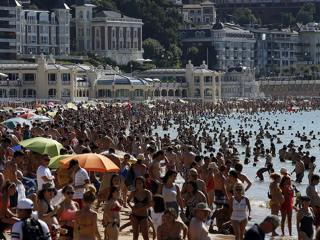 Хиляди плажуващи се насладават на слънцето и морето на плажа Ла Конча в Сан Себастиан, Испания, където температурите достигнаха 35 градуса.