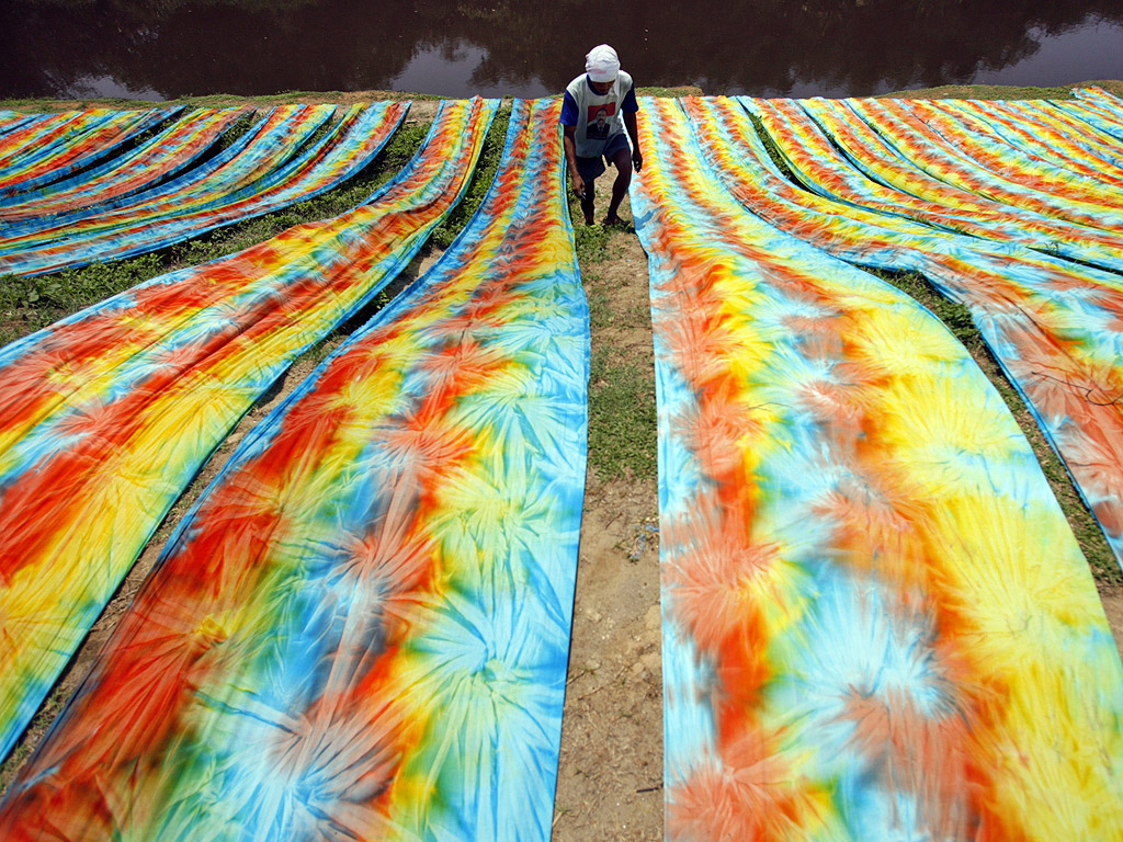 Индонезийски работник простира цветни тъкани на брега на река в Централна Ява, Индонезия