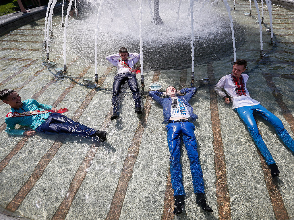 Ученици във фонтана на площад Независимост в центъра на Киев, Украйна празнуват завършване на училище