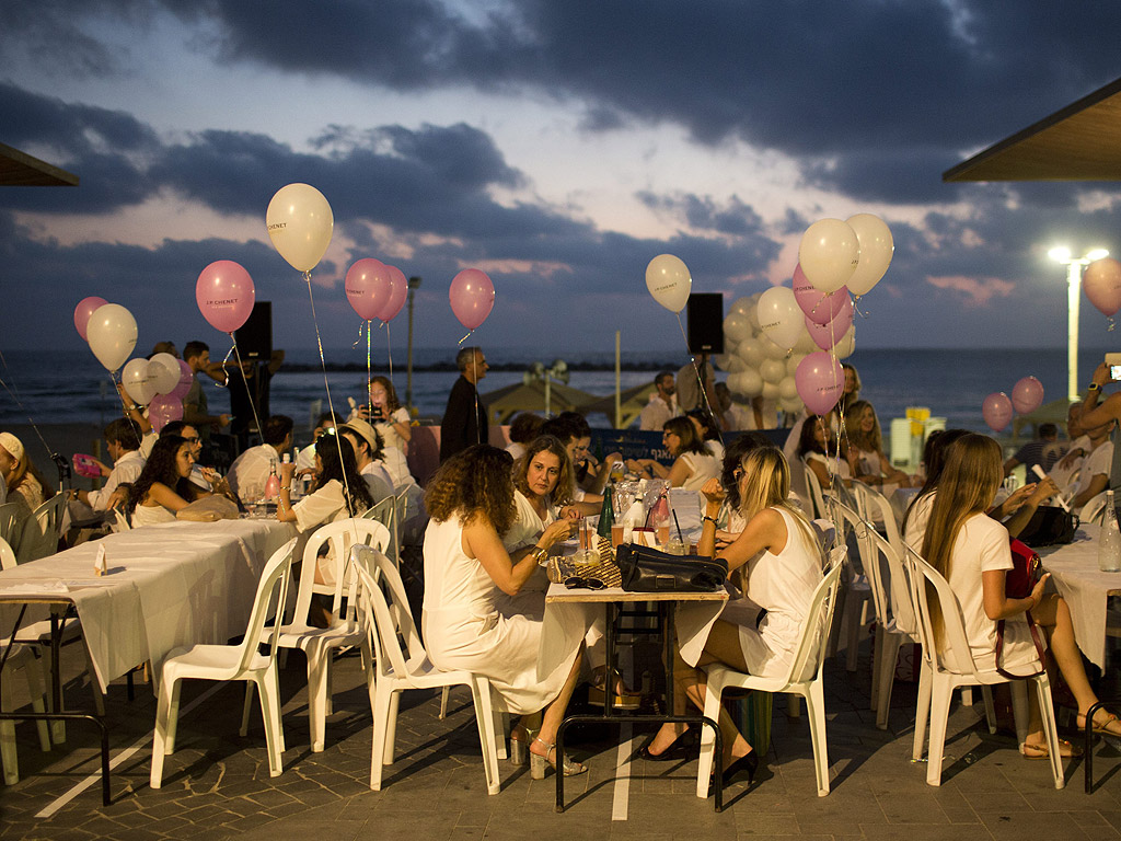 Хора облечени в бяло участват в "Тел Авив вечеря в бяло" в близост до плажа в Тел Авив, Израел, по време на откриването на фестивала "Бели нощи в Тел Авив"