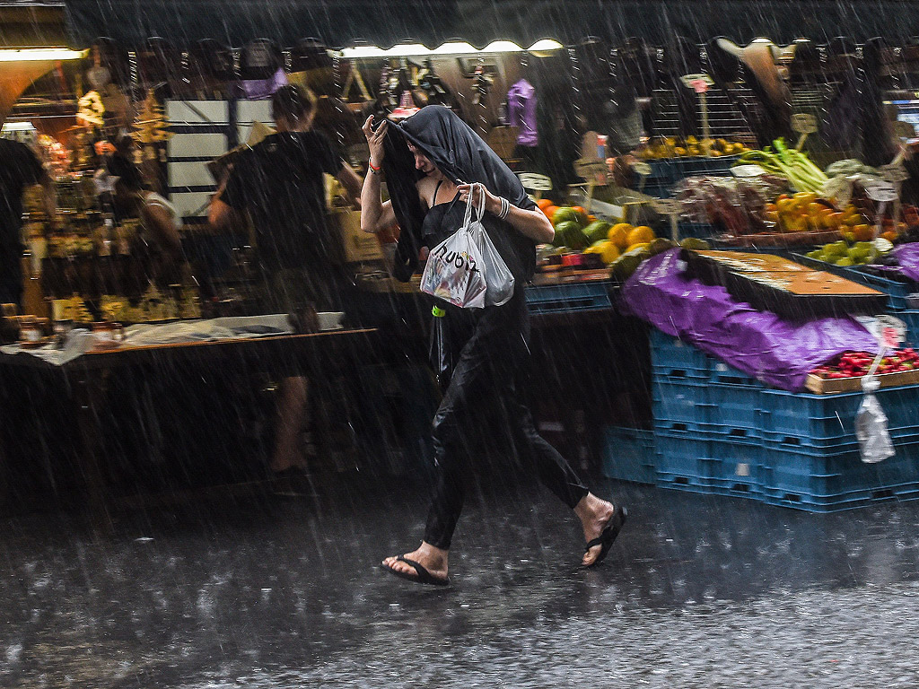 Жена бяга по време на силна буря на пазар в Централна Прага, Чехия. Обилни валежи и гръмотевични бури, засегнаха Чехия днес.