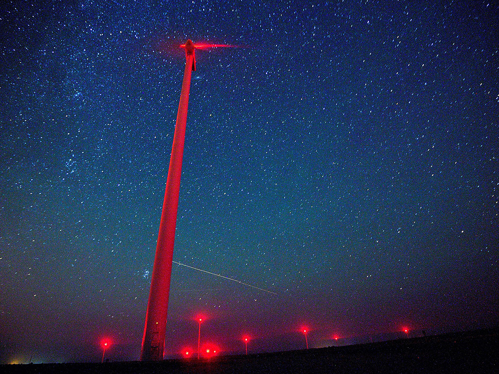 Метеор в нощното небе над вятърна турбина във "Вятърен парк Свети Никола" близо до Каварна, на 500км от София, България