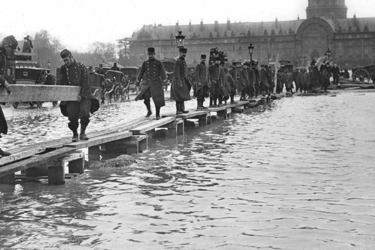 В края на януари 1910 г. след месеци на обилни валежи във Франция, в Париж река Сена пълни канализационните канали, тунелите на метрото, проправя си път до мазетата на хората и пропива напълно почвата.
За разлика от близките градчета, в които буйната река излиза от коритото си и залива всичко заобикалящо я, в Париж тя сякаш извира от самия град, за да го наводни.
За 10 дни водата достига до най-високото си ниво, а на 35-ия изчезва напълно. За щастие наводнението не отнема нито един живот. За сметка на това нанася щети на стойност над 400 млн. франка, равняващи се днес на 1.5 млрд.