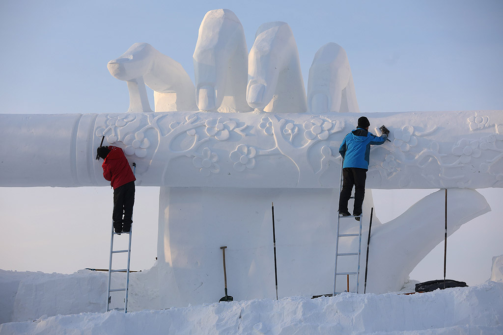 Хора разглеждат ледените скулптури, осветени от цветни светлини в град Харбин, Китай по време на 34-ия Международен фестивал на леда и снега. Около 180 000 кубически метра лед и 150 000 куб. метра сняг са използвани за изграждането на 800 000 квадратни метра скулптури за фестивалът, който ще продължи три месеца