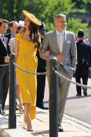 <p>Джордж Клуни, с чудесен официален костюм, и Амал - с невероятна жълта рокля и шапка.&nbsp;Обожаваме жълто и мислим, че Амал Клуни е взела чудесено решение при избора си на тоалет за кралската сватба.</p>