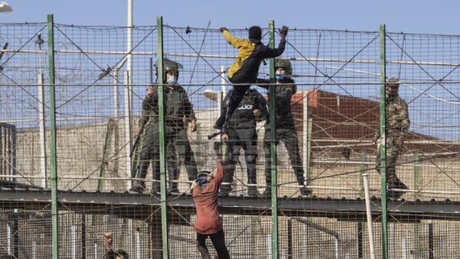 Мигранти се катерят по оградата, разделяща испанския анклав Мелиля от Мароко