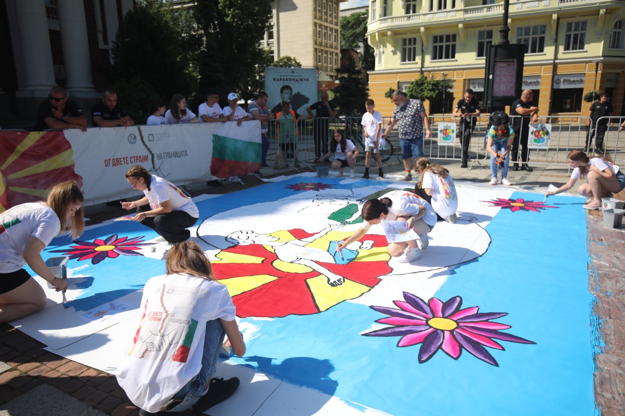<p>Млади художници от България и Северна Македония рисуват голяма картина пред сградата на Народния театър &bdquo;Иван Вазов&ldquo; в София, символизираща стремежа към единство между двете държави.</p>