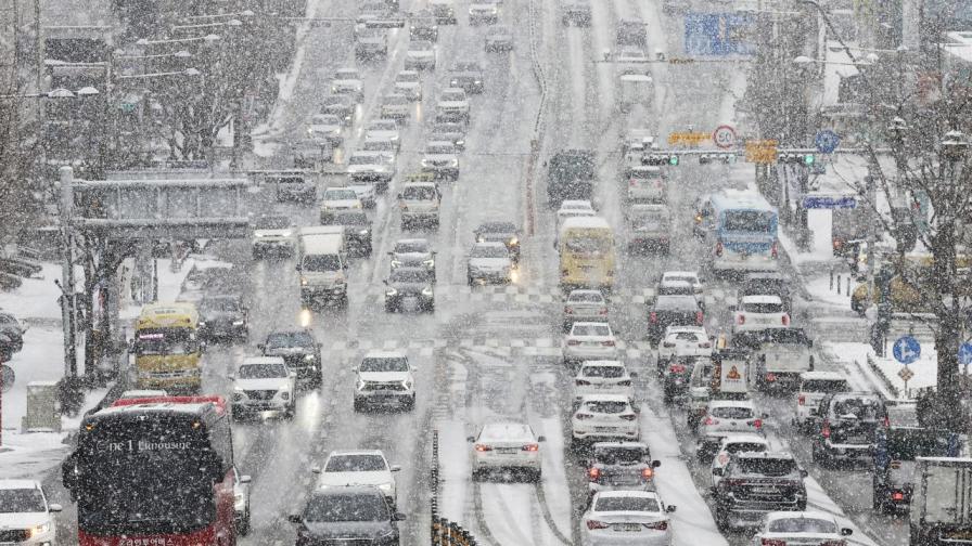 Автомобили преминават бавно при обилен снеговалеж в южнокорейския град Сувон