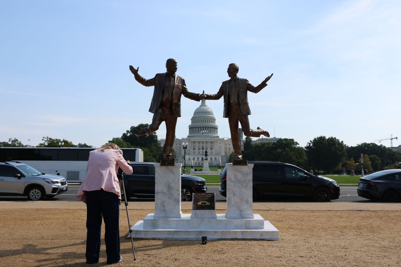 <p>Галерията представя новата бронзова статуя на National Mall, изобразяваща Доналд Тръмп и Джефри Епстийн в радостна поза. Инсталацията предизвика оживени реакции и дискусии, като акцентира върху миналата връзка между президента и осъдения трафикант.</p>
