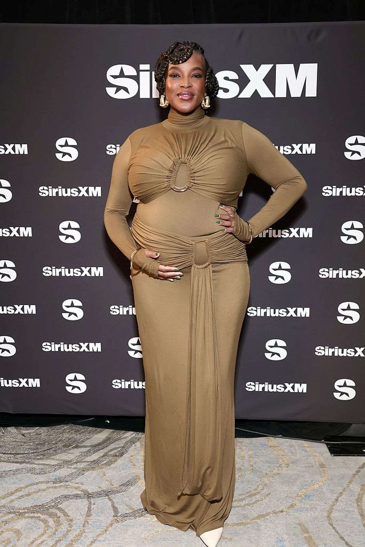 <p><strong>Уунми Мосаку</strong></p>

<p>Звездата от &bdquo;Грешници&ldquo; сияеше в маслиненозелена рокля до пода с изрязани детайли и драпирана материя в областта на талията, която подчертаваше красиво коремчето ѝ. Уунми избра кремави обувки на висок ток с остър връх, златни гривни и златни обеци за финален щрих.</p>