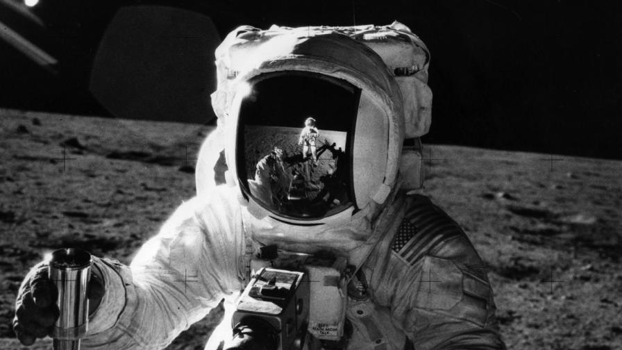 Астронавтът от мисията „Аполо 12“ Алън Бийн държи контейнер с лунна почва, събрана по време на повърхностната дейност извън модула. На лявата си китка той носи списък със задачи, а на гърдите му е монтирана камера Hasselblad за заснемане на мисията. В огледалния визьор на шлема му се отразява неговият колега Чарлз Конрад, който прави тази историческа снимка.