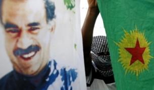 Маскиран кюрд държи флага на ПКК до портрет на Абдула Йоджалан по време на демонстрация