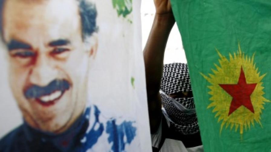 Маскиран кюрд държи флага на ПКК до портрет на Абдула Йоджалан по време на демонстрация