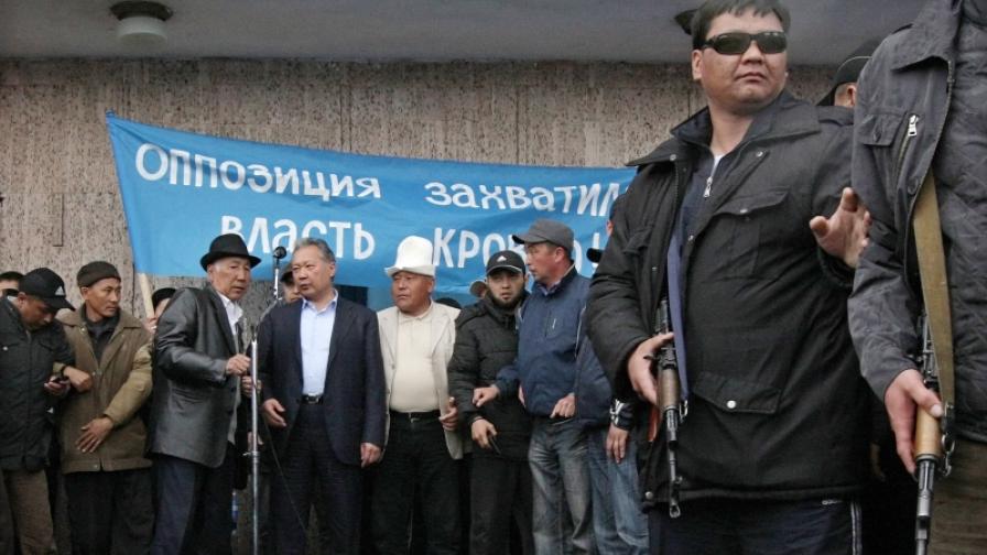 Охраняваният от въоръжени лица свален президент на Киргизстан Курманбек Бакиев (вдясно от микрофона) се готви да говори пред група симпатизанти