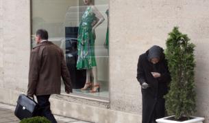 Възрастна жена проси пред лъскав бутик в центъра на София. Наредба на общината забранява просията в рамките на града.