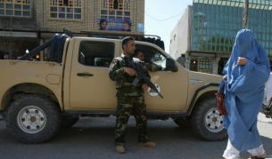 Афганка, скрита в бурка, минава край войник от редовната армия в размирния град Херат в Западен Афганистан