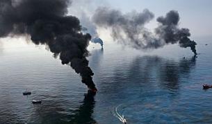 Пушек се издига от нефта по повърхността на водата, който екипите по почистването изгарят близо до взривената сондажна платформа