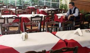 Келнер очаква клиенти в празен ресторант в центъра на Атина