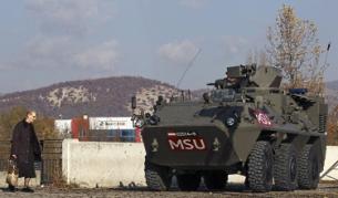 Жена минава покрай бронирана бойна машина на австрийските сили на НАТО в Косово