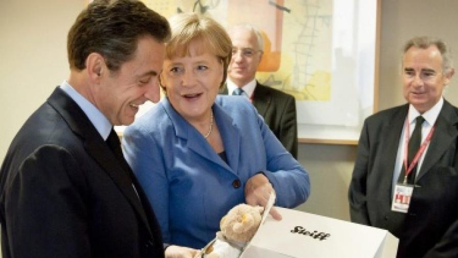 Германският канцлер Ангела Меркел подарява на френския президент Никола Саркози мече по случай раждането на дъщеря му