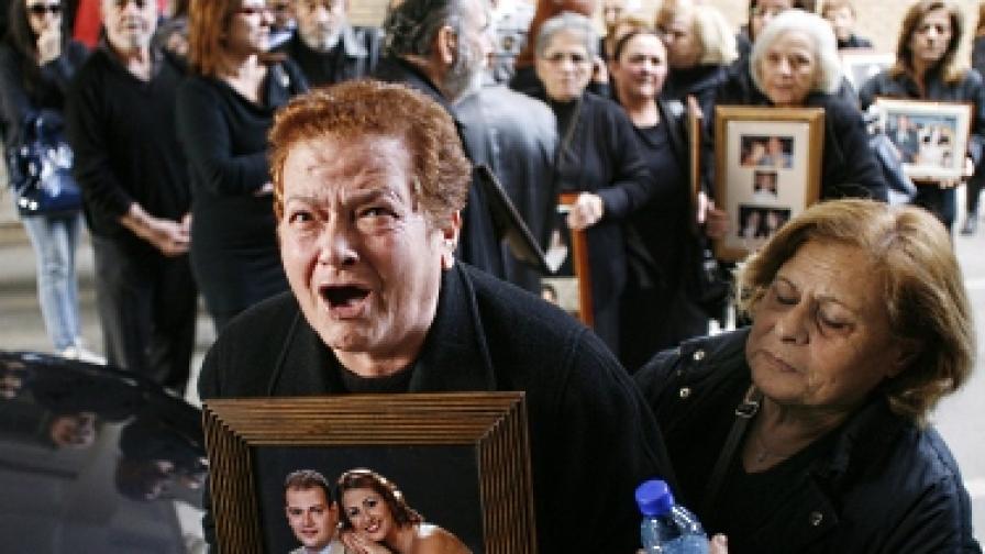 Роднини на жертвите от катастрофата държат техни снимки при протест срещу оправдателната присъда на кипърския съд