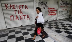 Жена минава покрай затворен магазин в центъра на Атина, на който е изписано 'Затворен завинаги'