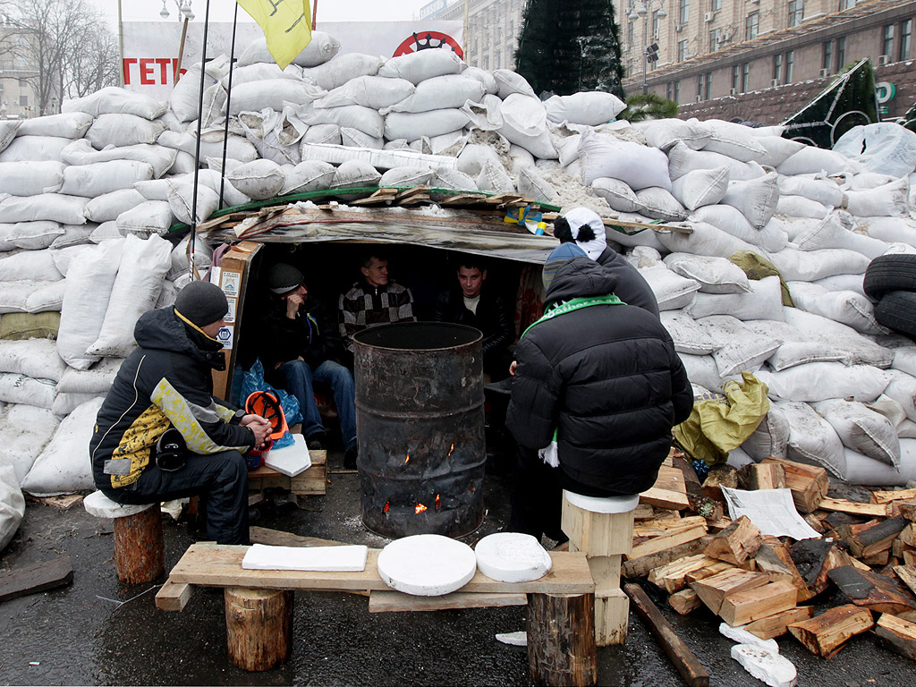 Проевропейски протестиращи в Киев се топлят около варел на една от барикадите в украйнската столица.