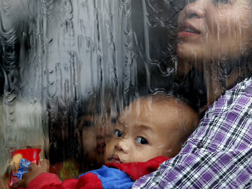 Дете гледа през процореца на автобус, опитващ се да пресече наводнен път на юг от Манила, Филипините, на 20 август. При наводненията в града са загинали седем души, а 130 хиляди са загубили дома си.